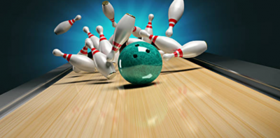A bowling ball smashes into the pins sending them all flying for a strike